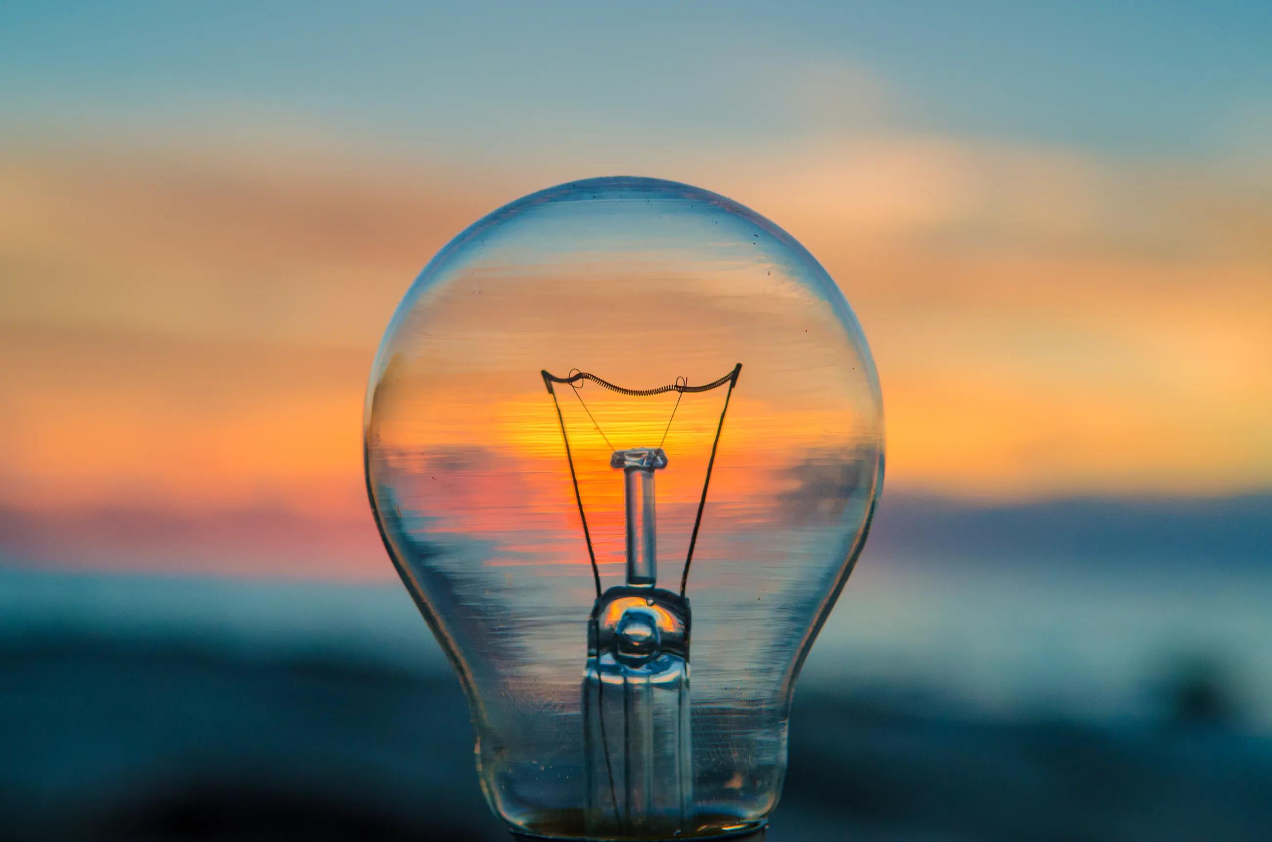 a lightbulb with the ocean at sunset in the background
