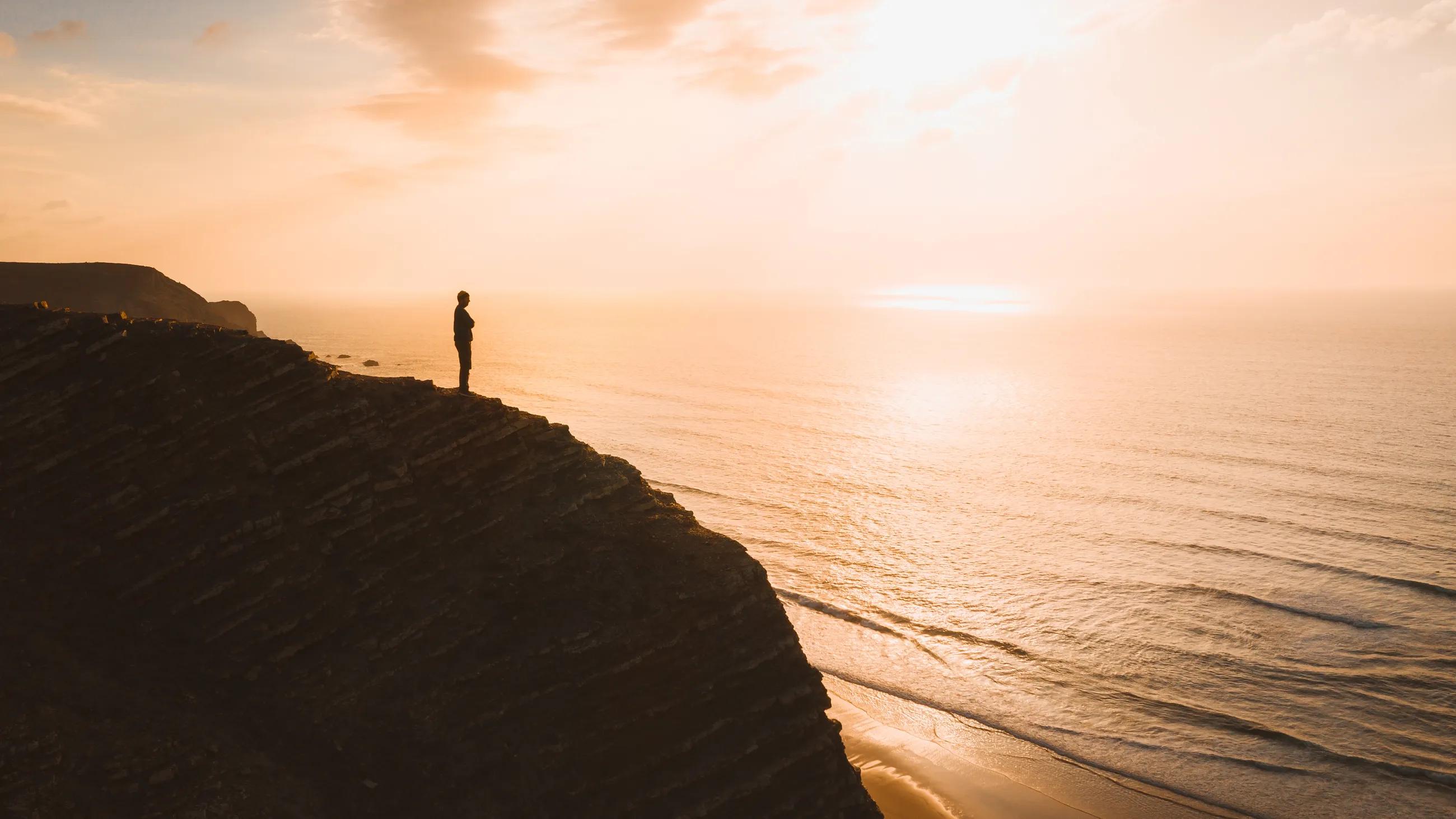 Man standing on a cliff over the ocean