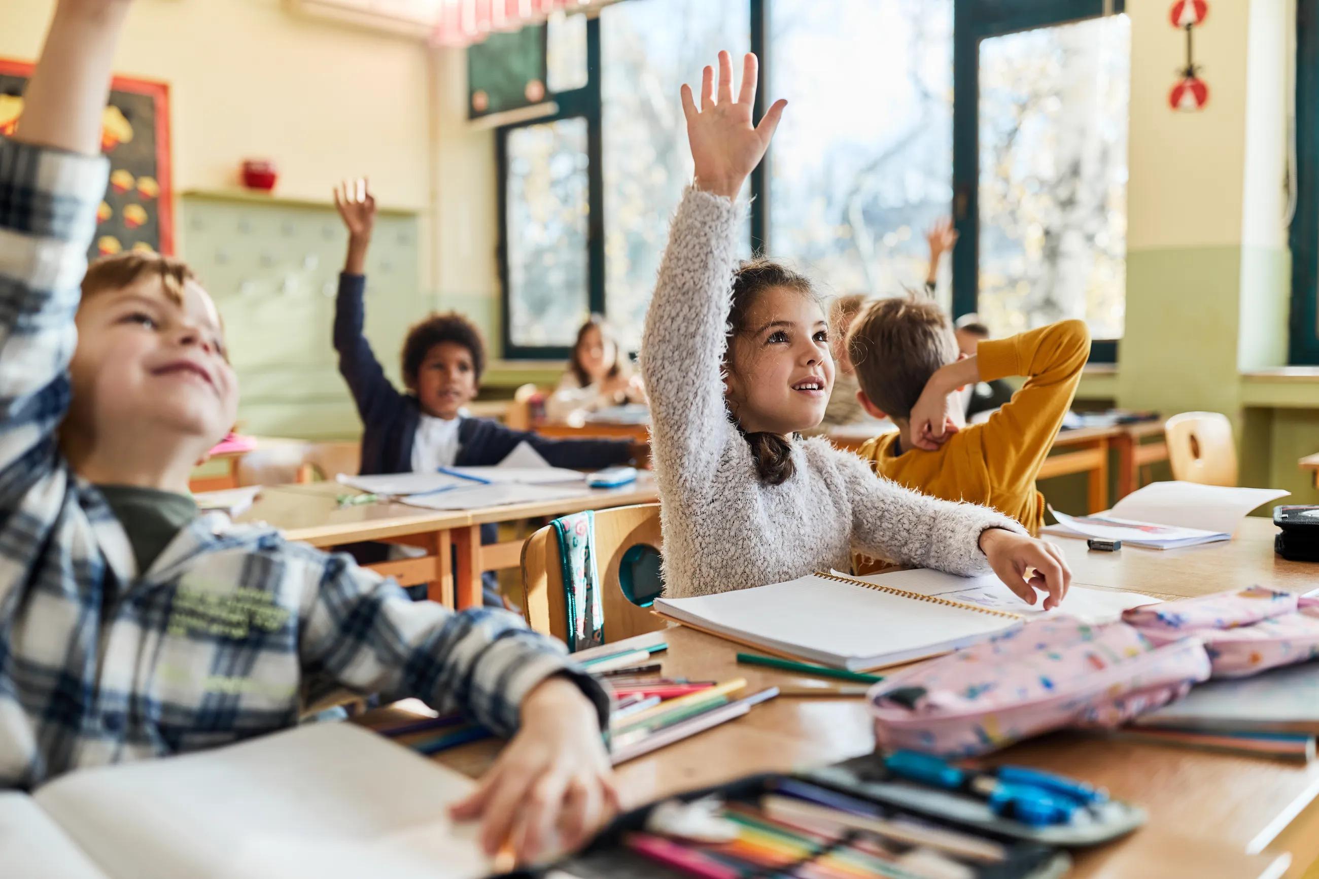 children raise their hands in a classroom