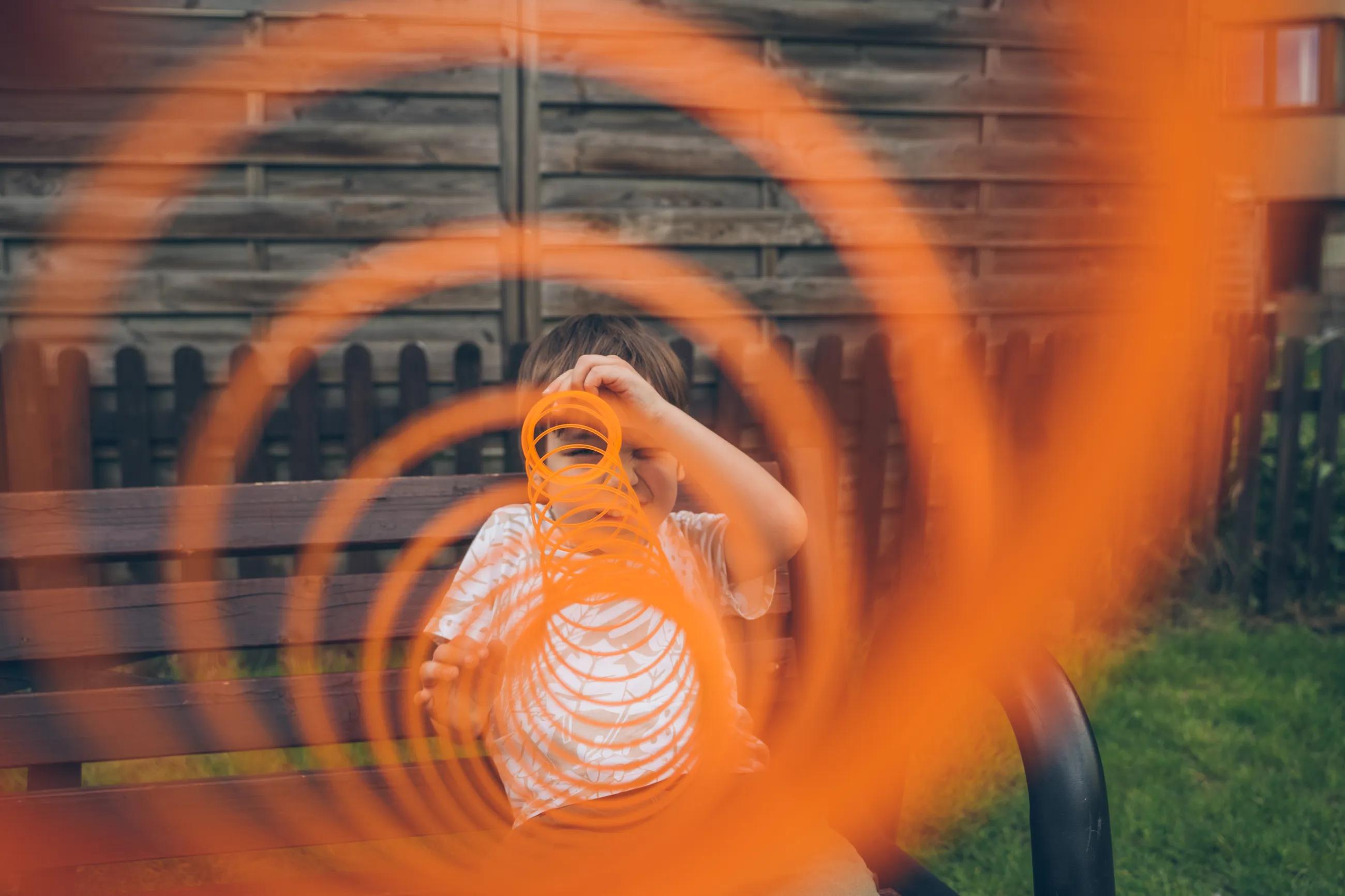 Boy looking through spring toy outdoors